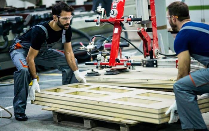 Workers Lifting Items in Factory